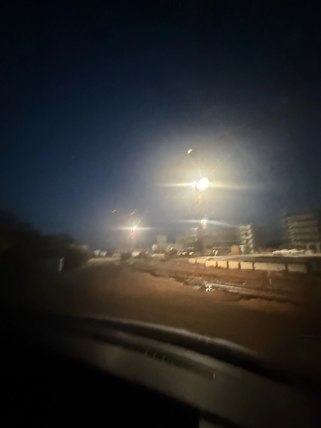 Fugentechnik Buchen - Bau - Verschwommene Nachtansicht einer Baustelle mit beleuchteten Kränen und Gebäuden unter dunklem Himmel