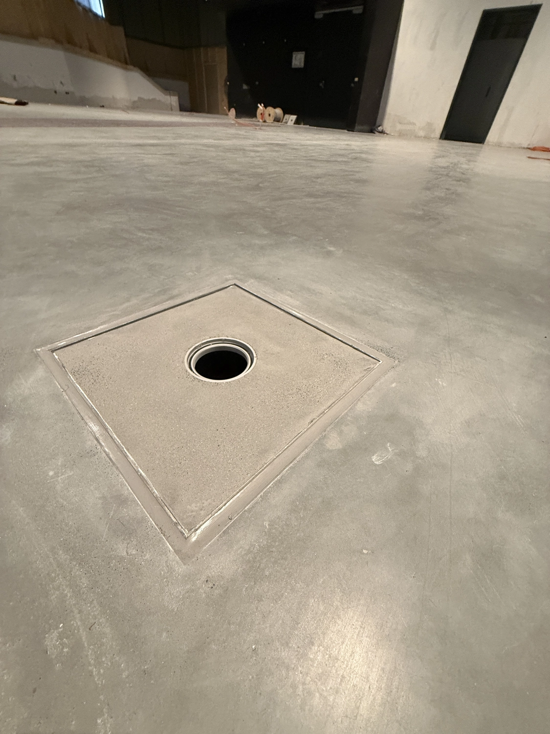 Fugentechnik Buchen - Bau - Betonboden mit quadratischem Ablaufdeckel mit kreisrundem Loch in der Mitte in einem Innenraum