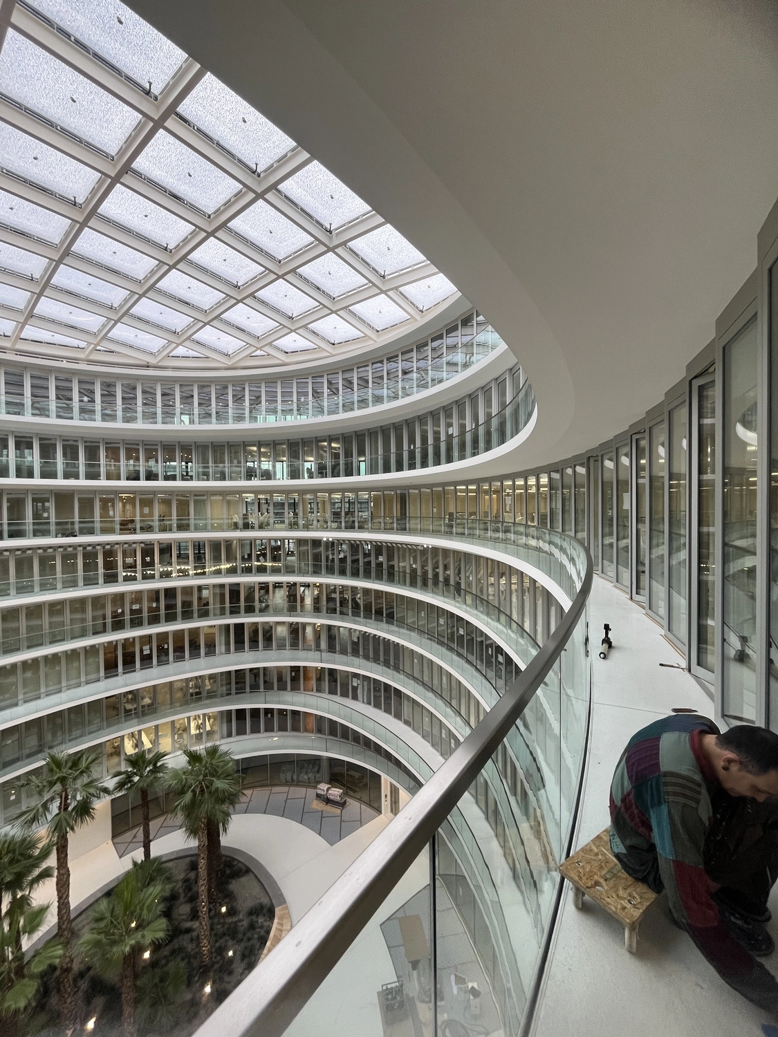 Fugentechnik Buchen – Bau – Modernes, mehrgeschossiges Bürogebäude mit geschwungenen Glasgeländern, großem Oberlicht und Palmen im Atrium