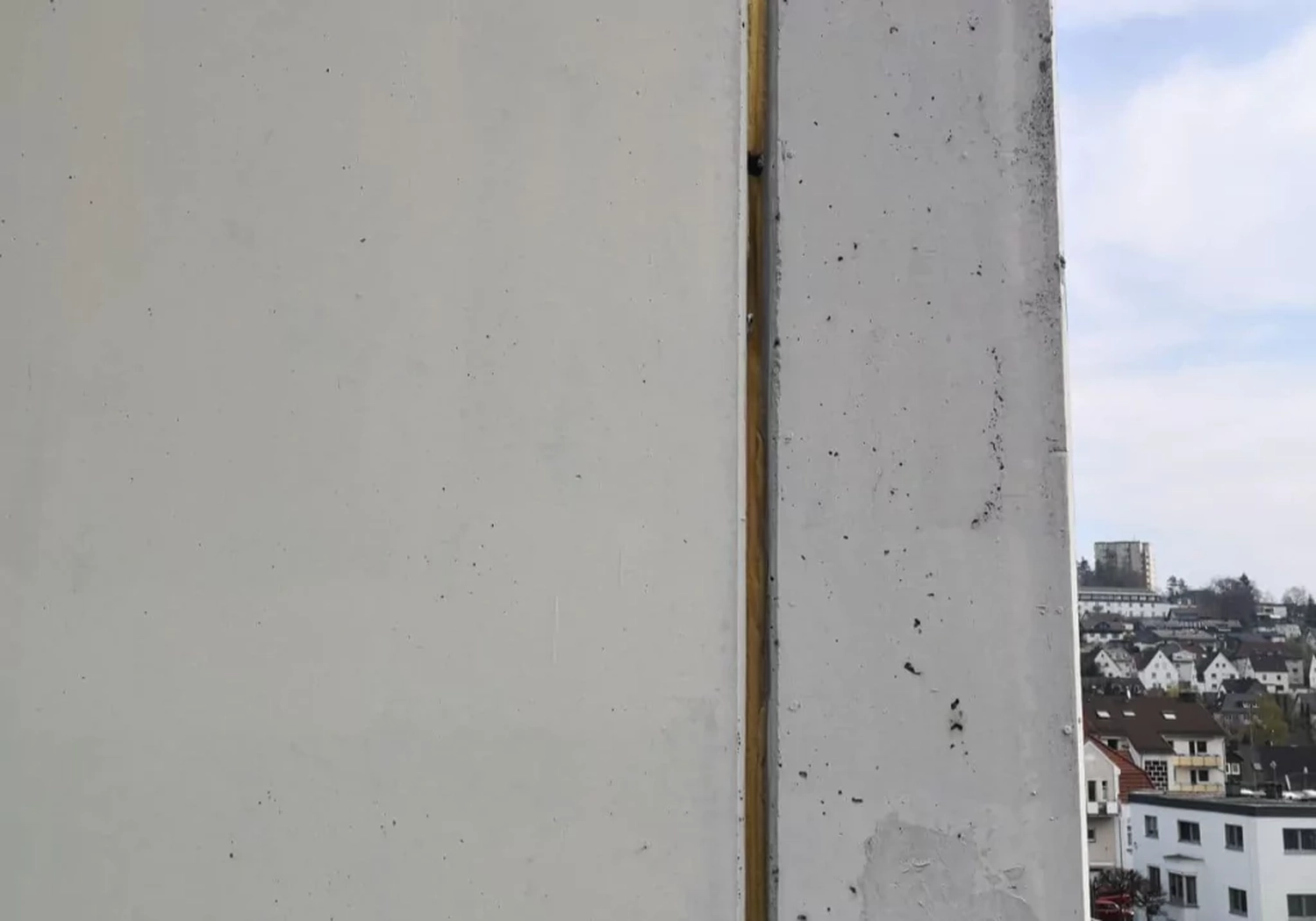 Fugentechnik Buchen - Bau - Nahaufnahme zweier aneinandergrenzender Betonwandelemente mit einem schmalen Spalt dazwischen und einer Stadtlandschaft im Hintergrund