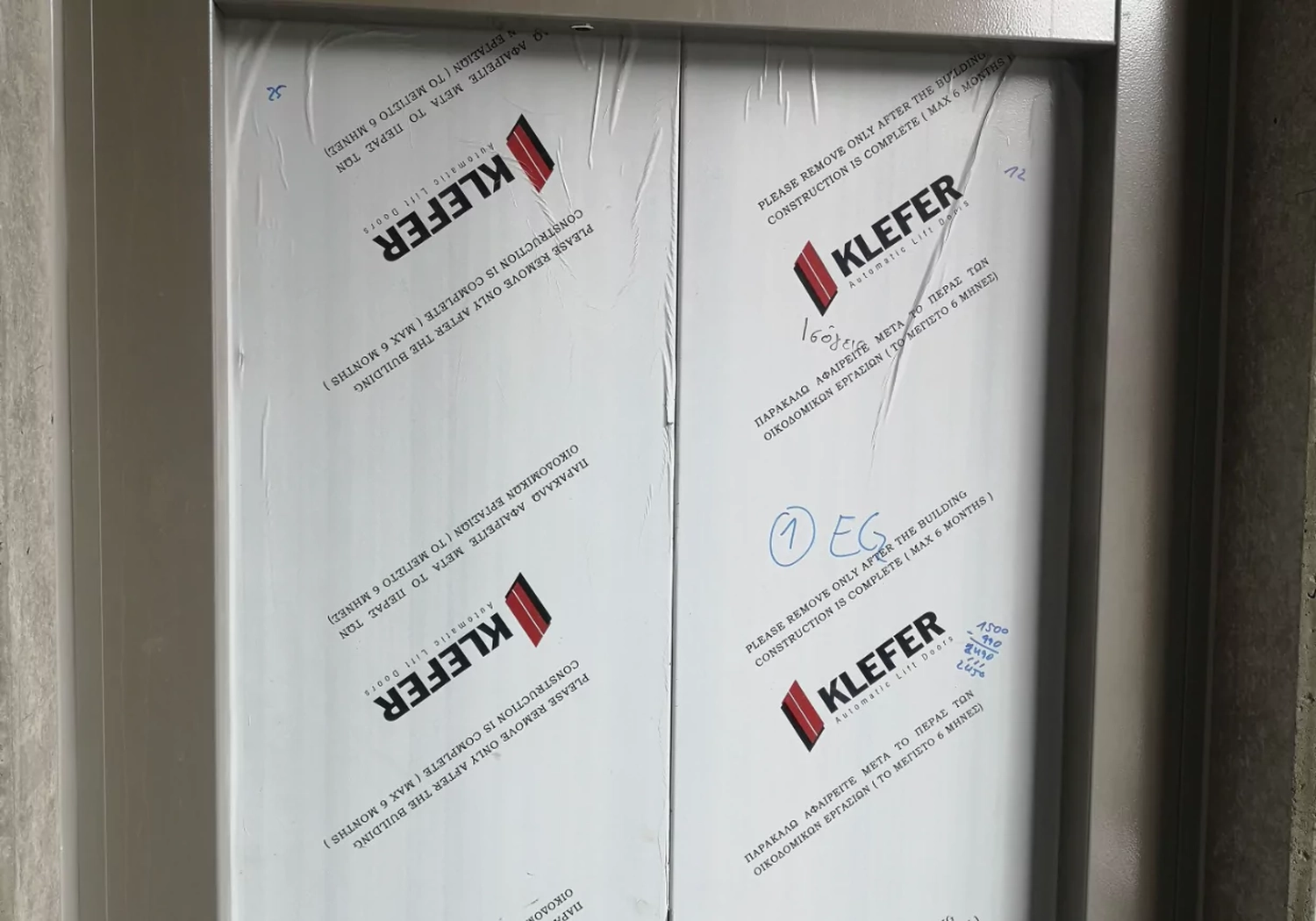 Fugentechnik Buchen - Bau - Nahaufnahme einer automatischen KLEFER-Lifttür, die mit Schutzfolie, Anleitungen und handschriftlichen Notizen versehen ist.